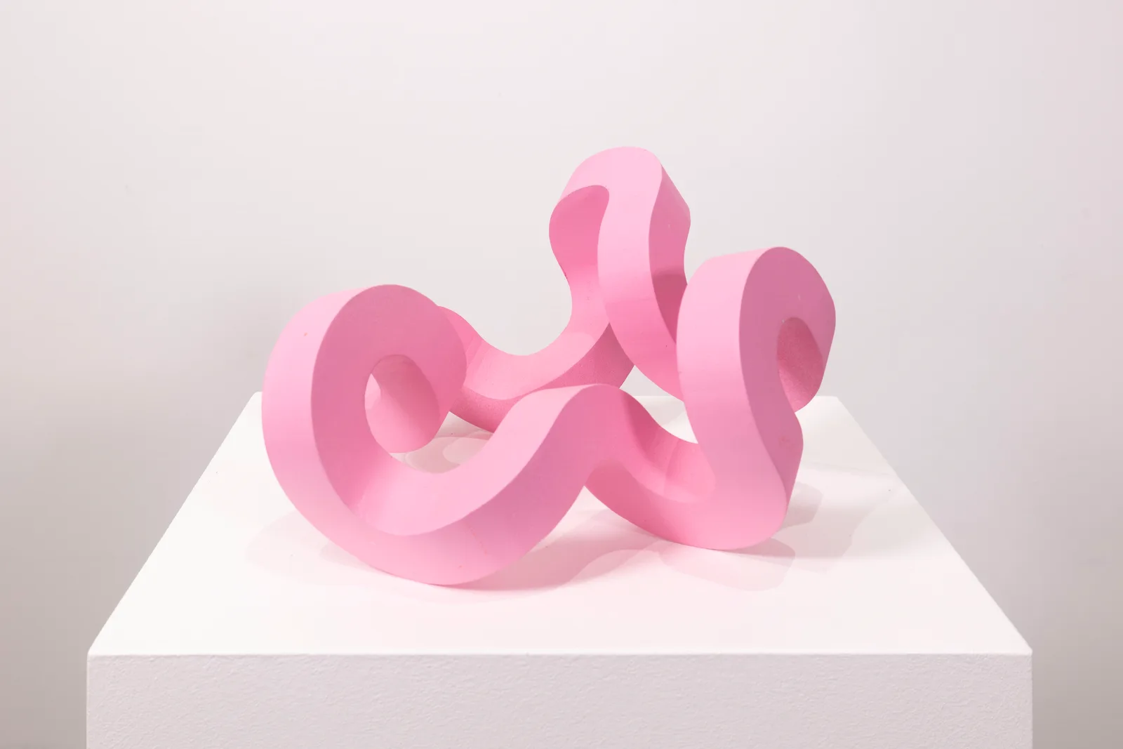 A bright pink sculpture by Jacob Dahlgren of a curved looping structure made from PLA plastic
