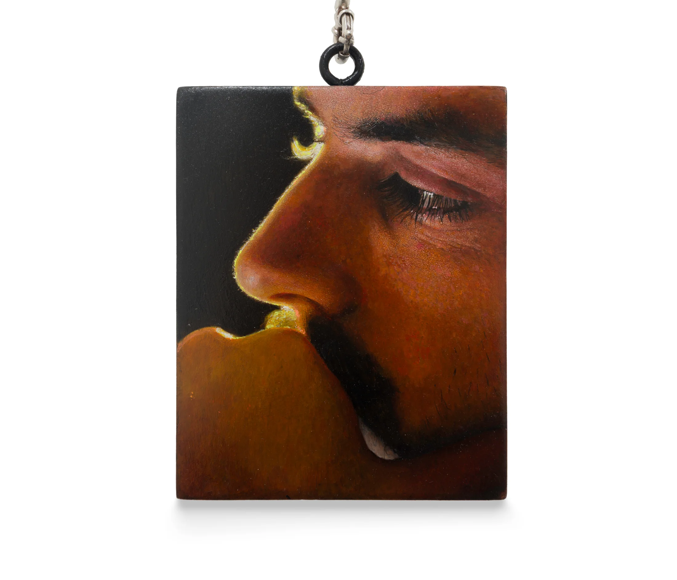 a painting by Ki Yoong of a close up of a male face against a dark background which hangs from a silver necklace