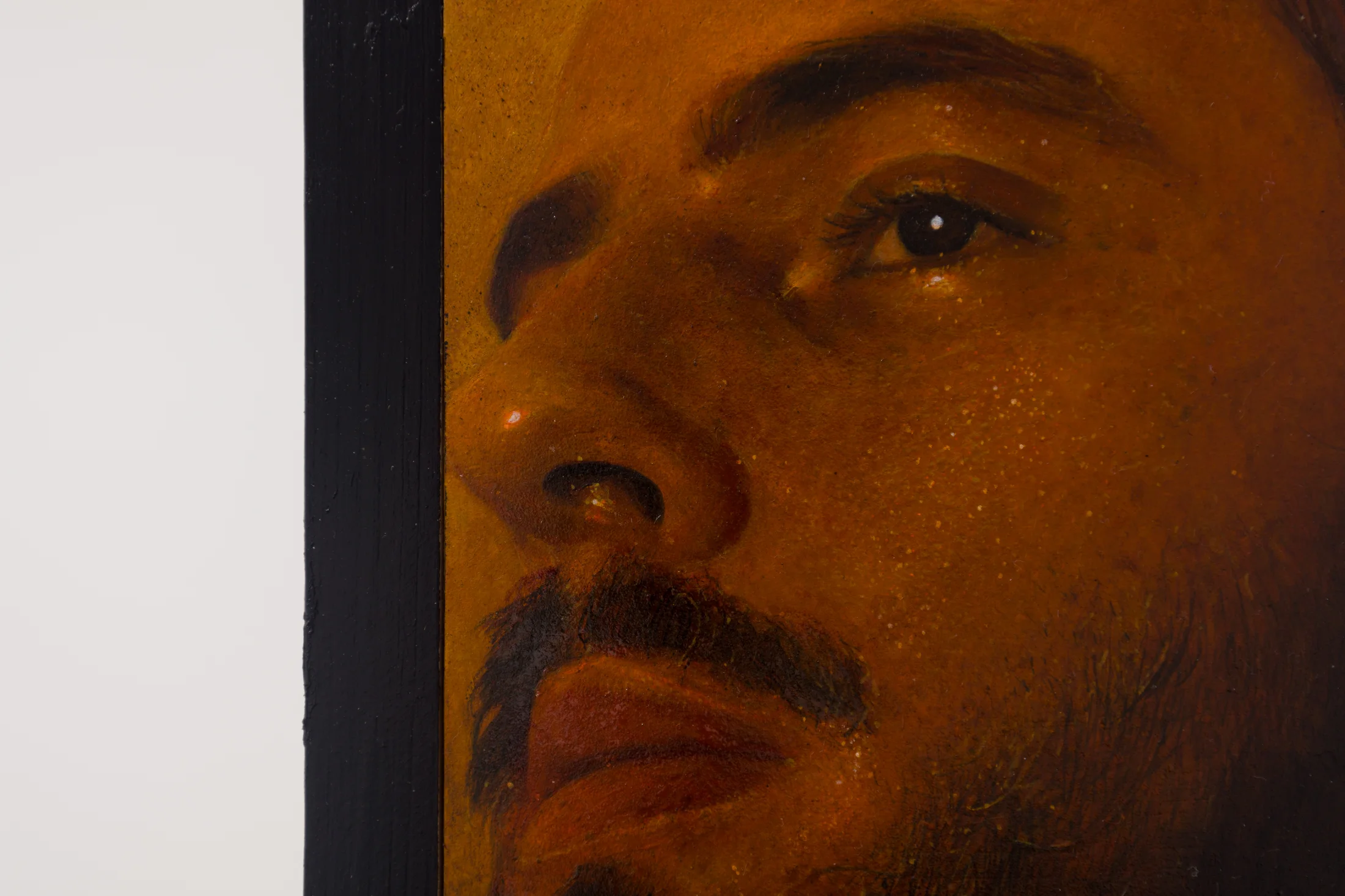A painting by Ki Yoong of a softly lit young man's face with steel brackets attached to the top and bottom