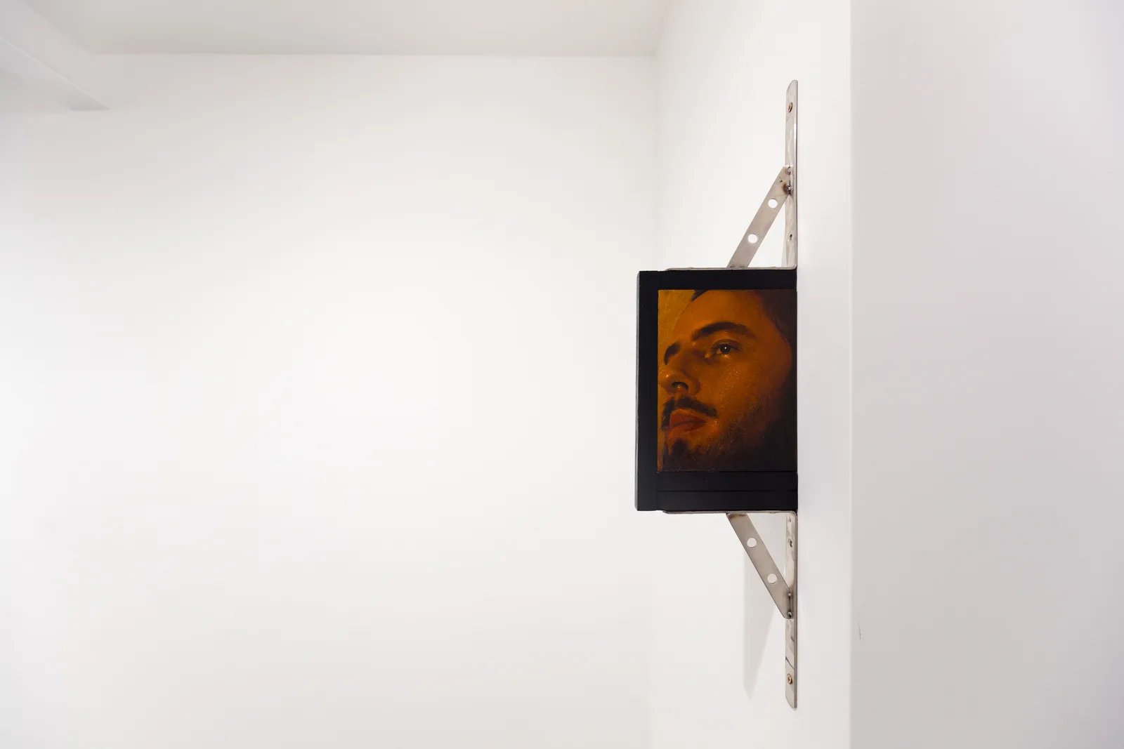 A painting by Ki Yoong of a softly lit young man's face with steel brackets attached to the top and bottom