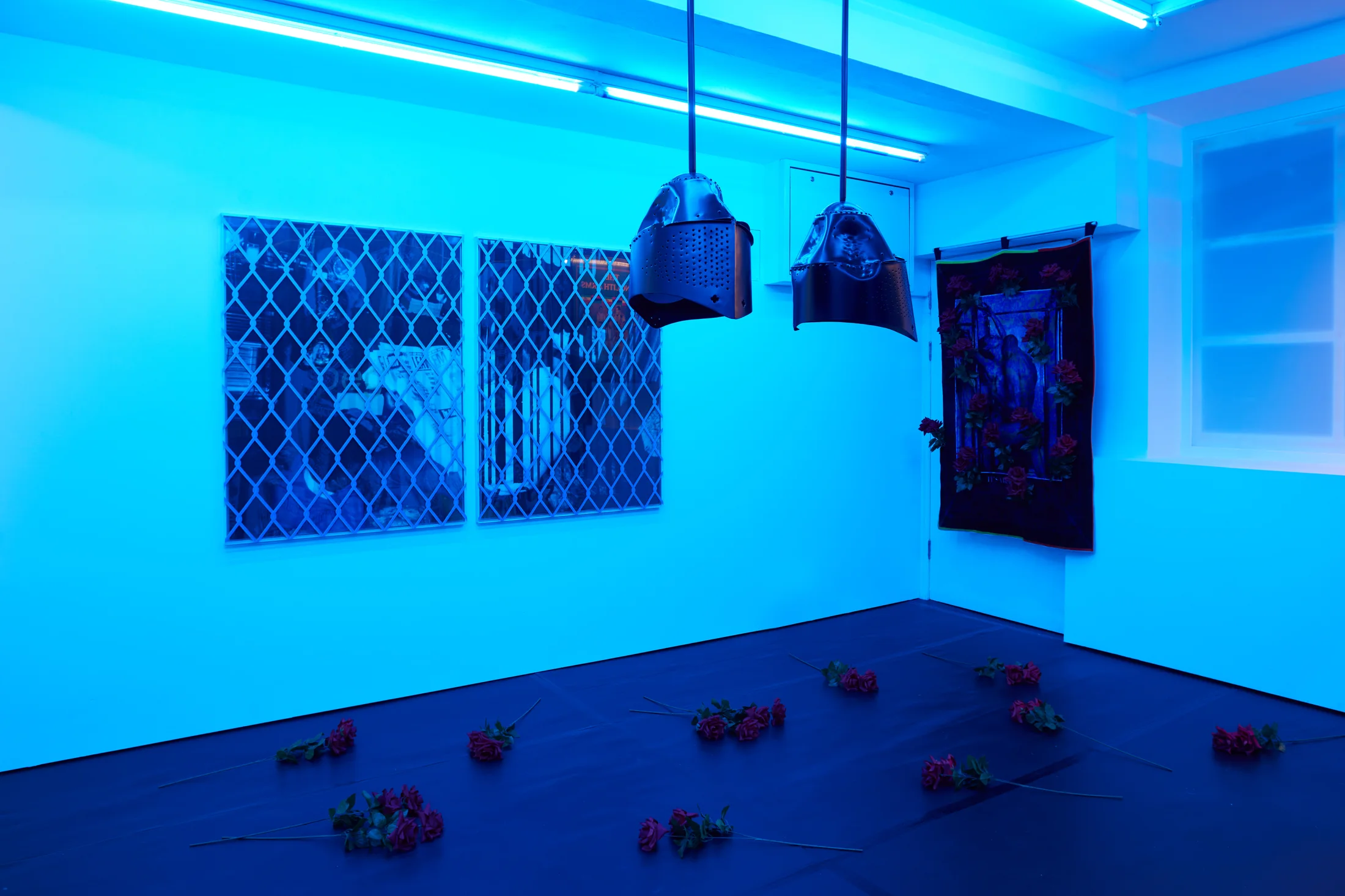 Installation images of Simeon Barclay's exhibition at Workplace in London, artworks, sculpture and video are cast in filtered blue light of a night club