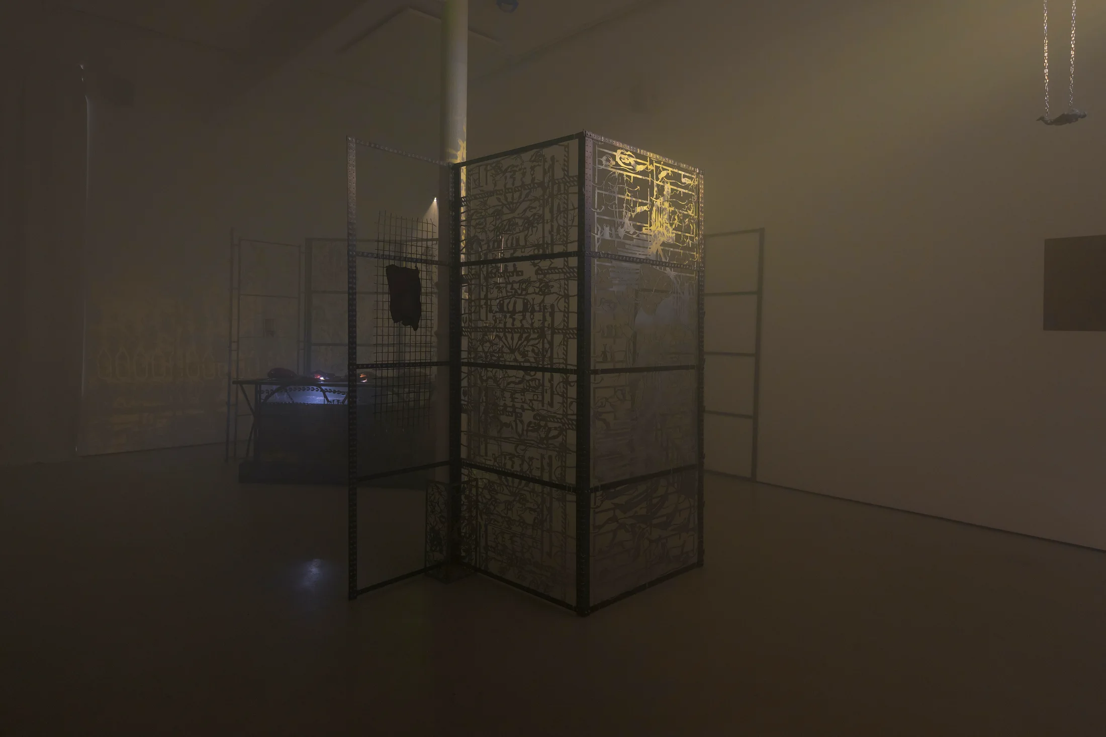 An installation by Hazel Brill including a water tanks filled with a dark liquid laser cut steel dividers, mouth-blown glass objects, projections and lights