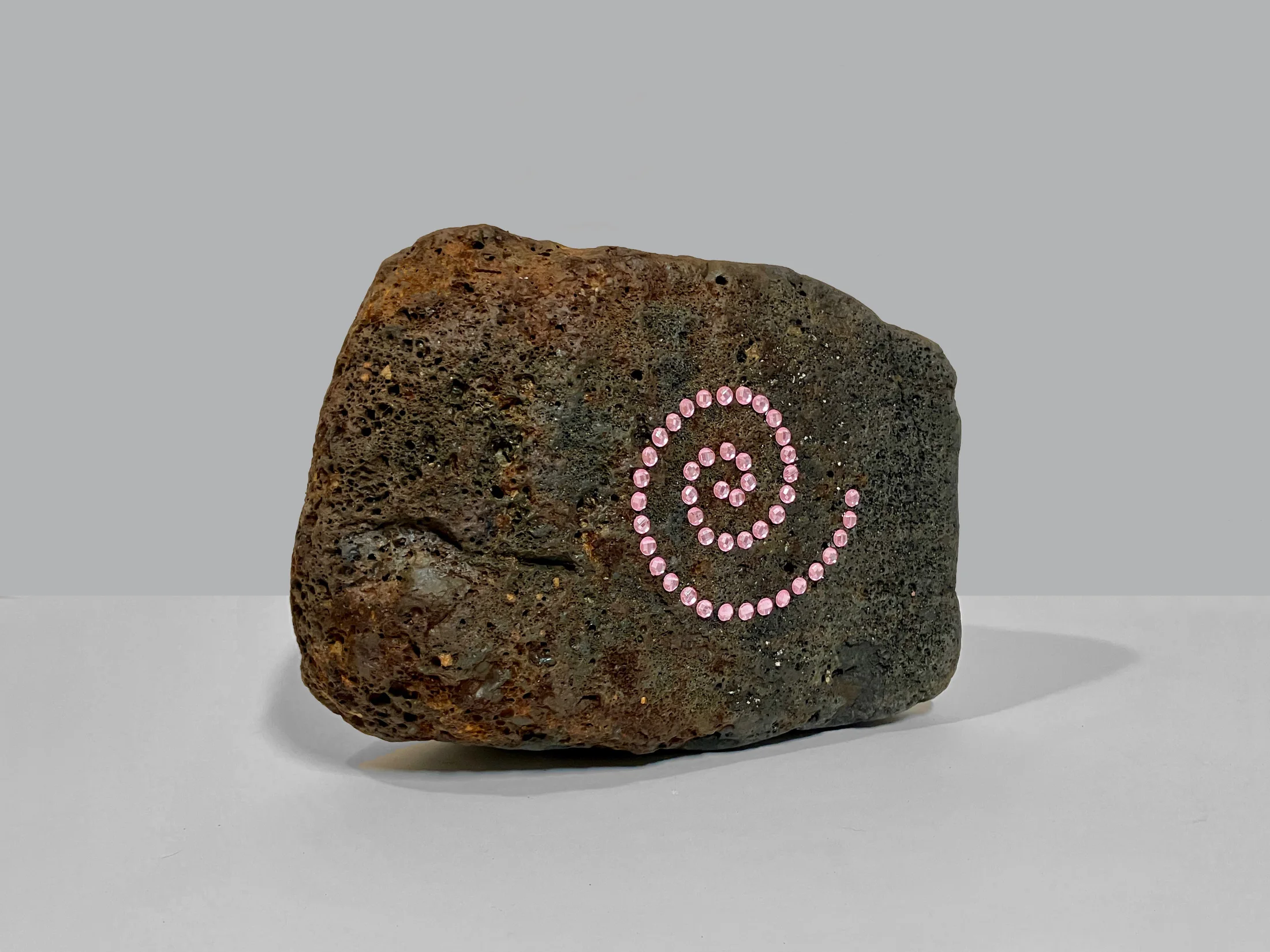 A sculpture by Eric Bainbridge of a rock with a spiral of diamantes attached to the face