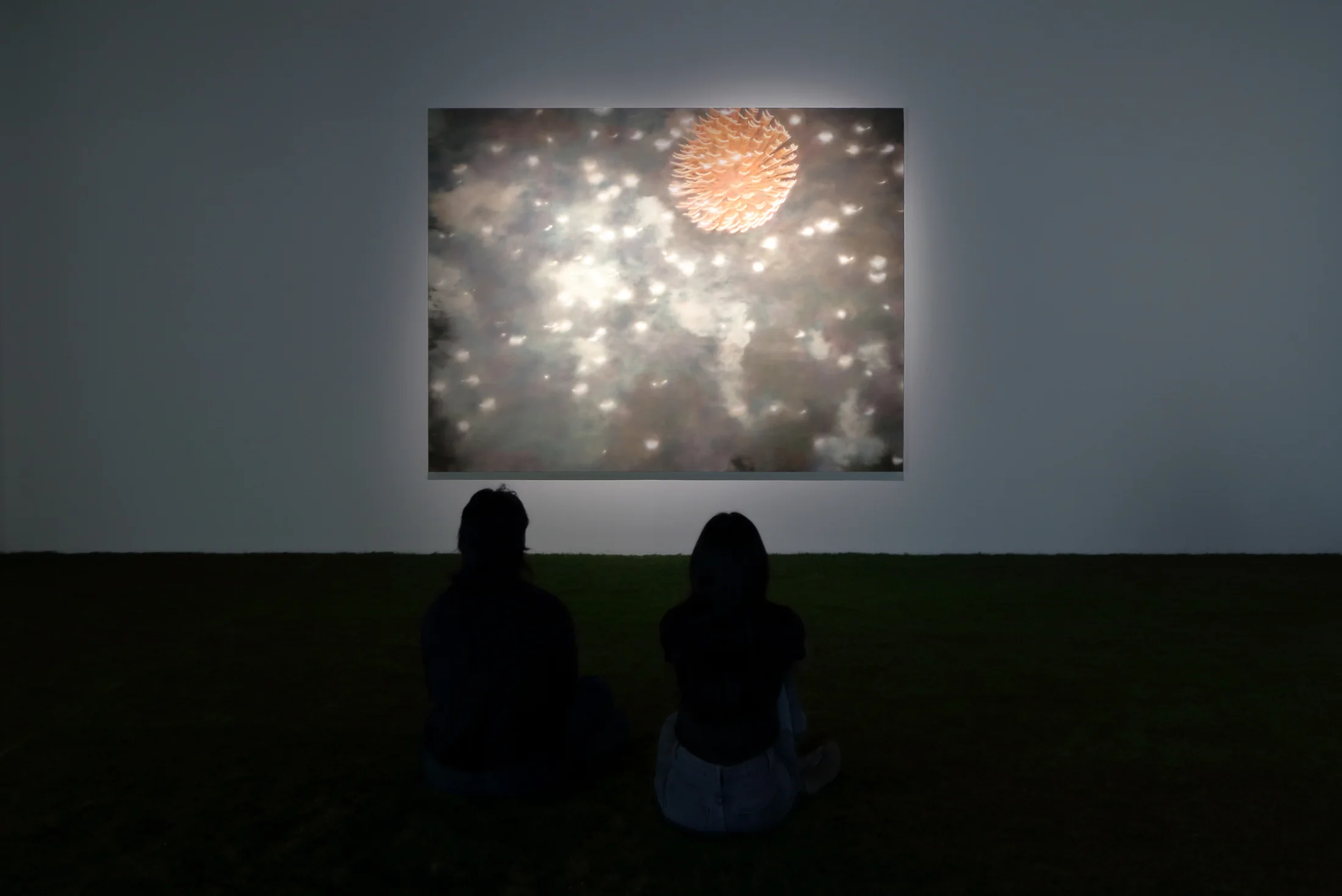 Installation view of a dark room with a painting by James Prapaithong softly spotlit