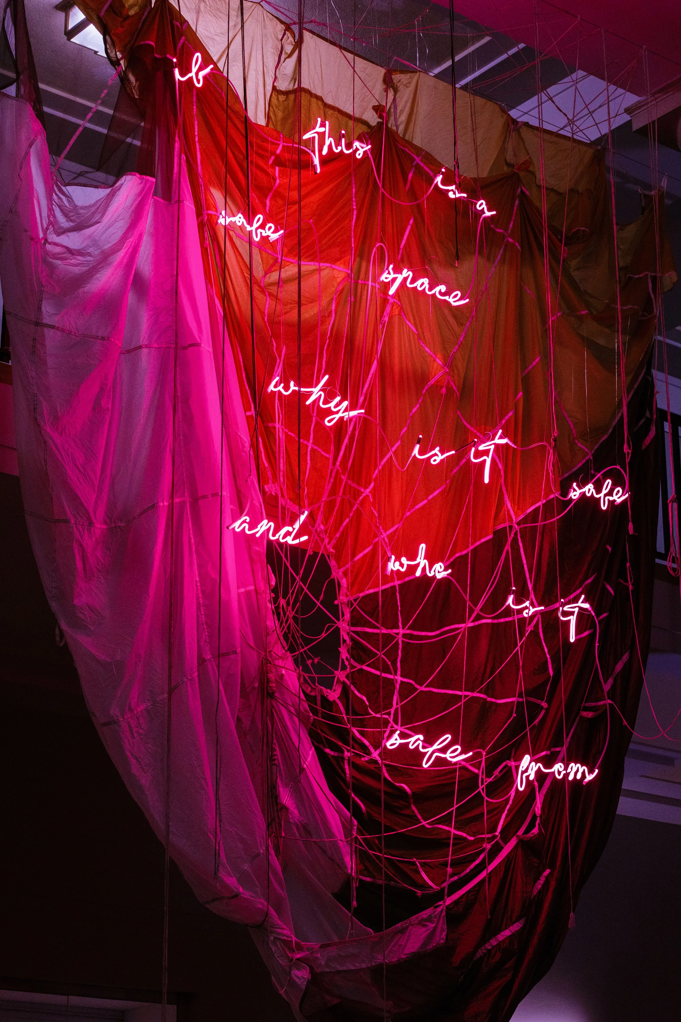 An installation by Simeon Barclay of a hanging parachute with red neon words
