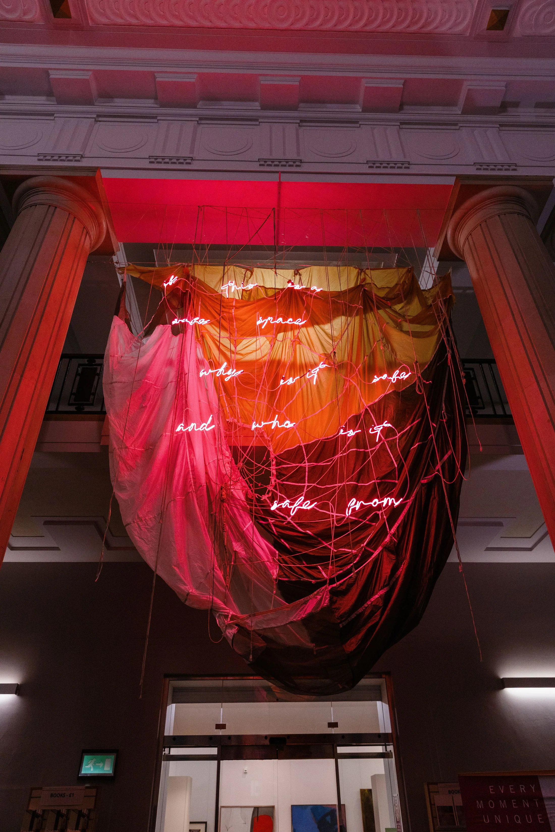 An installation by Simeon Barclay of a hanging parachute with red neon words